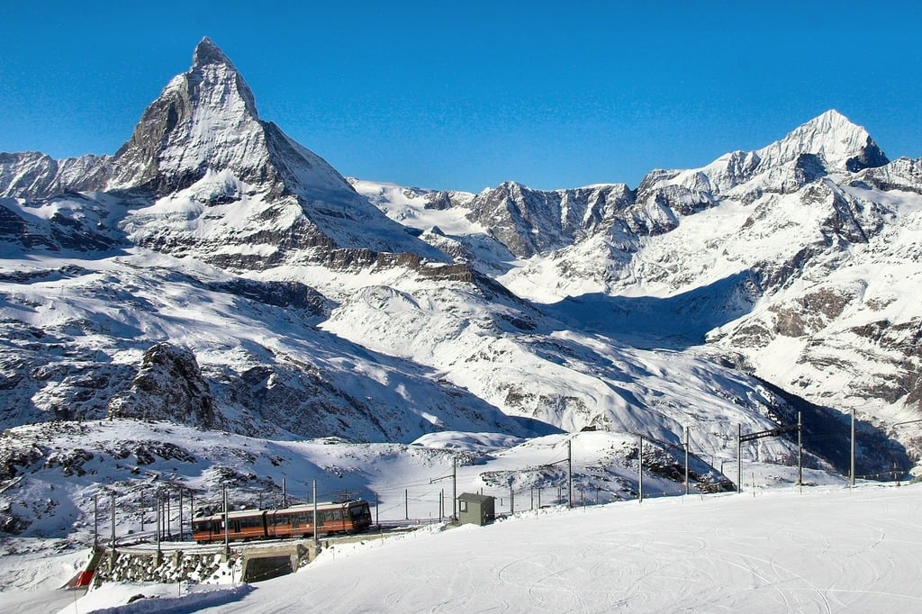 A train traveling down a snow covered mountain side. Gornergrat matterhorn mountains.